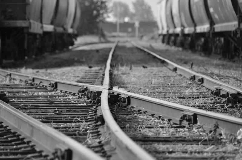 A railroad switch in overgrown grass — tracks diverging as a metaphor for critical decision points in AI deployment